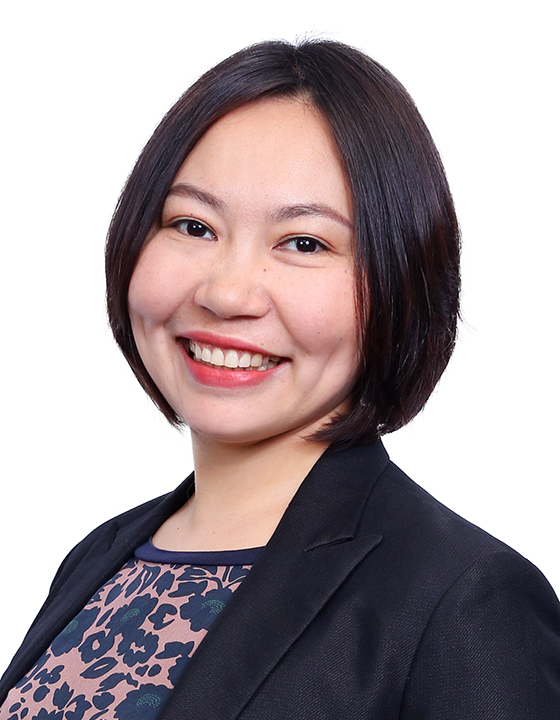 Professional headshot of a smiling woman with short black hair, wearing a dark blazer over a patterned top.
